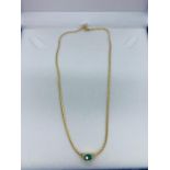 An 18ct yellow gold necklace (marked 750) with central Emerald with three stone Diamond shoulders.