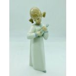 A Lladro figure of a girl playing a musical instrument.