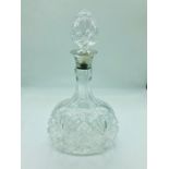 A cut glass decanter with hallmarked silver neck.