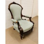 An upholstered Victorian open armchair with carved frame