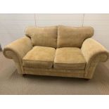 A two seater beige fabric sofa