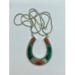 A silver horseshoe necklace set with coral and malachite panels