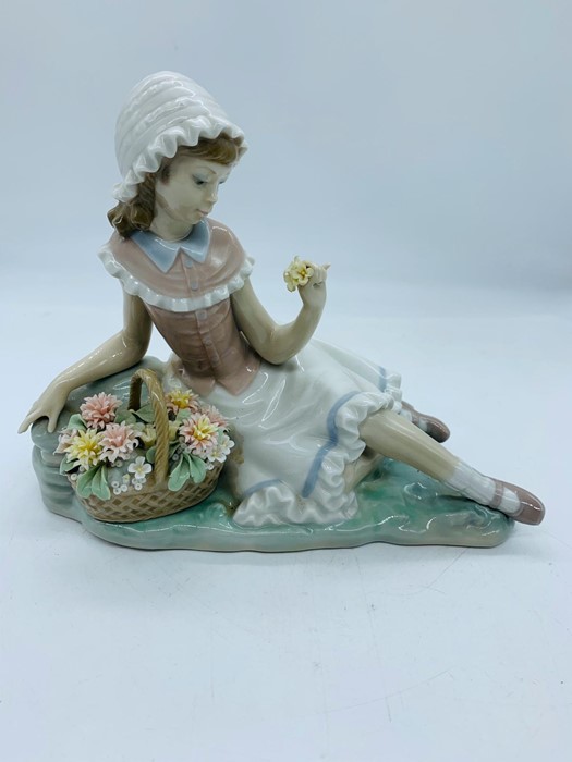 A Lladro figure of a girl sat with basket of flowers