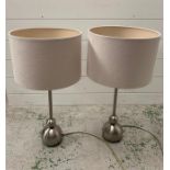 A pair of brush metal contemporary lights with white shades