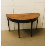 A mahogany half moon table on four tapered legs