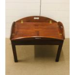 A mahogany butlers tray with brass hinges on it's own stand