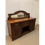 An ornate sideboard with carved panel doors and brass drop handles