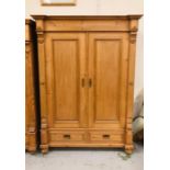 A large pine double wardrobe with inner shelf and hanging rail with two lower drawers on bun feet (