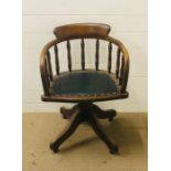 A swivel office/captains chair with green leather seat and screw tilting mechanism on brass castors