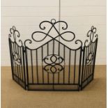 A large black wrought iron folding fire screen