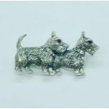 A silver brooch in the form of two dogs with ruby eyes