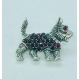 A silver dog brooch with semi precious stone jacket and ruby eyes