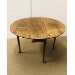 An oval drop leaf dining table on tapered legs with turned out feet (H70cm D100cm W114cm