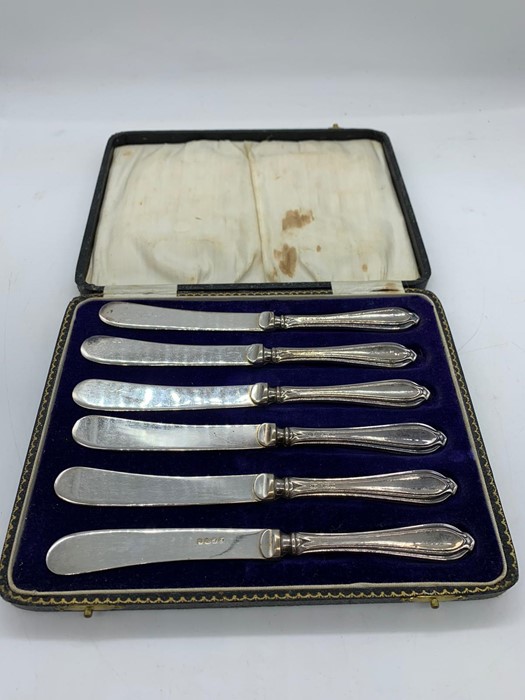 A Boxed set of six butter knives with silver hallmarked handles.