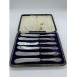 A Boxed set of six butter knives with silver hallmarked handles.