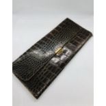 A large brown crocodile leather glove and handkerchief wallet with brass fastening.