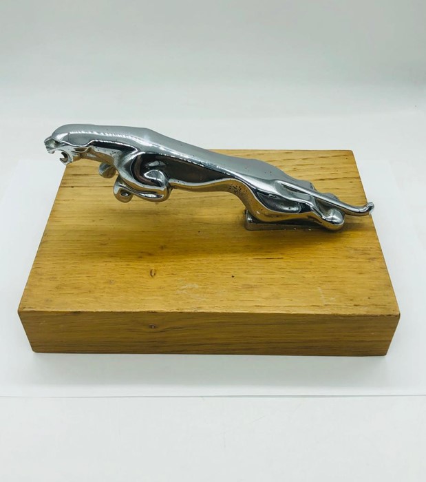 A Jaguar Chrome figure on a wooden stand.