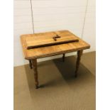 Solid pine kitchen table with insert and original winder, on turned legs with brass castors