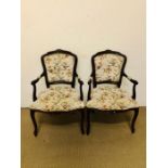 A pair of reproduction salon chairs upholstered in a flora and fauna design fabric with brass stud