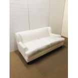 An off white two seater upholstered sofa on four bun feet designed and upholstered by Gary Andrews