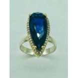 A silver dress ring set with a large faux Sapphire surrounded by CZ's