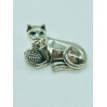 A Silver Cat figure with emerald eyes playing with a ball of wool.