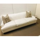 A large off white three seater upholstered sofa on six bun feet designed and upholstered by Gary