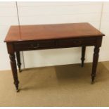 A mahogany hall table with two drawers on turned legs with brass castors and brass drop handles