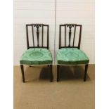 A pair of dining chairs with green seats