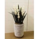 A rattan effect plant pot with an artificial flower arrangement standing approx. 140cm tall