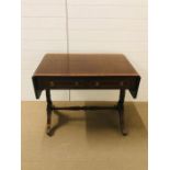 A drop leaf library table with inlaid top on splayed supports with stretcher between on brass lion