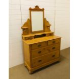 A pine dressing table with tilting bevelled mirror on bun feet with castors
