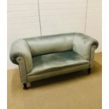 A two seater Chesterfield on castors covered in a silver grey velvet fabric