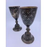 A pair of white metal goblets with a cloisonné style finish.