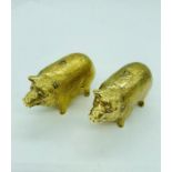 A pair of gold plated condiments in the form of pigs