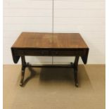 A drop leaf hall table on splayed supports with brass castors and two drawers