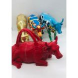 Three highly decorative cows and a resin red bull in the style of a hang bag