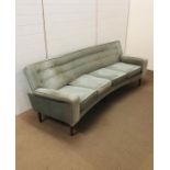 A mid century curved button back four seater sofa on a six tapered legs upholstered in a pale