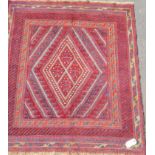An Afghan tribal hand-knotted burgundy Kazak wool rug with multi-coloured lozenge decoration, double