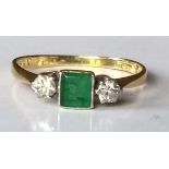 A diamond and emerald ring on 18ct yellow gold: step-cut emerald 4.6mm x 4mm flanked by two