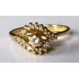 A diamond-set crossover ring on 18ct yellow gold, centrally set with a round brilliant-cut diamond