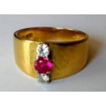 A stylised gold three-stone ruby and diamond dress ring; the central round mixed-cut ruby 4.4mm