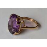 A 9ct yellow gold oval amethyst ring in a claw setting, 17.73 x 13.05 x 9.17mm, 12.96 carat on a