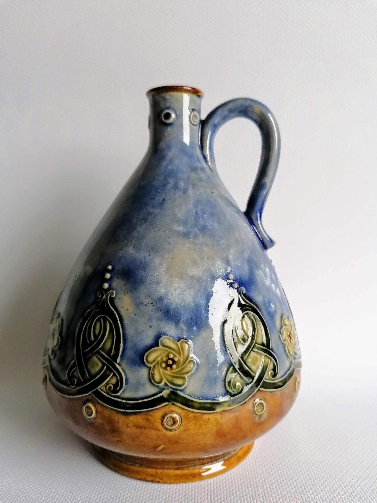 An Edwardian Doulton Lambeth whisky jug with mottled blue-ground and Celtic knot decoration,