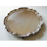 A Sheffield circular silver salver with pie crust rim on three scroll feet by James Dixon & Sons