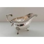 A George VI silver sauce boat with gadroon rim, leaf cap scroll handle on hoof feet by Collingwood &