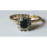 A 9ct yellow gold sapphire and diamond cluster ring, the emerald-cut sapphire 5.6 x 4.4 x 2.11mm,