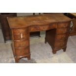 A reproduction mahogany serpentine twin pedestal desk Having a cross banded top above a central