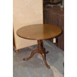 A Georgian oak tripod table The circular top raised on a ring turned baluster shaft with downswept