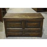 An 18th Century oak coffer Having a rectangular plank top above a carved frieze and two panels,